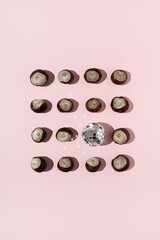 Horse chestnuts and disco ball arranged on pink background. Flat lay autumn concept.