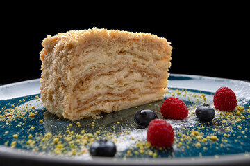 Piece of Napoleon cake with berries, on a dark background