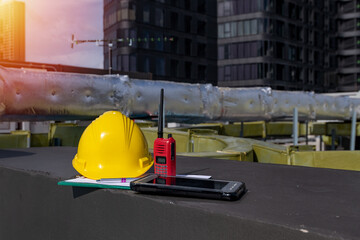 Yellow helmets, radio communication and smart phone put on the floor are the background of the...