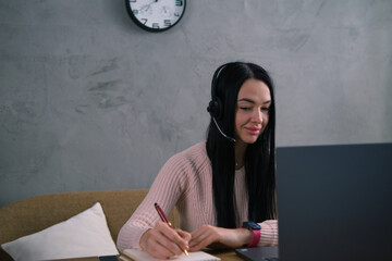 A girl with a headset works at a computer or studies remotely