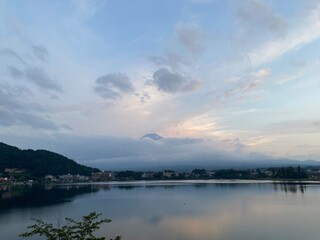 Fototapeta na wymiar 6pm, tip of Mt. Fuji’s head started to peak behind the thick clouds, showing us bless and saying hello after days of cloudy weeks. We were lucky. Year 2022 August 26th, Yamanashi Kawaguchiko Lake.