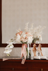 The bride's wedding bouquet of roses and orchids and the bride's shoes