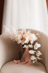 The bride's wedding bouquet of roses and orchids on a chair