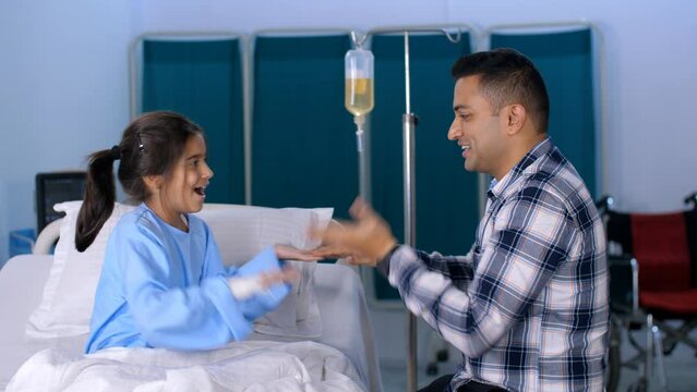 A caring Indian father playing and spending time with his little girl child in a hospital room - childhood game  . A sick Indian child with his single father - hospital treatment  medical treatment...