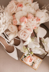 The bride's wedding bouquet of roses and orchids and the shoes and wedding rings