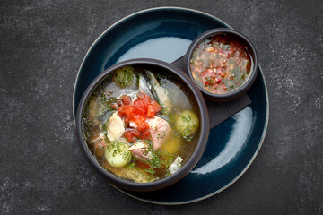 Salmon fish soup with spicy sauce on a dark background