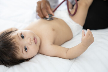 Obraz na płótnie Canvas doctor using stethoscope for pediatrician examining baby tummy on the bed