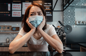 Asian woman coffee shop business owner Stressed and disappointed from The effects of the coronavirus pandemic resulting in business losses