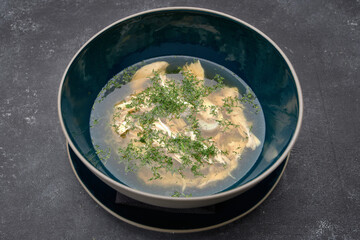 Chicken broth with dill, consomme, on a dark background