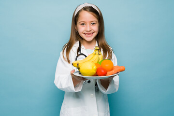 Cheerful little girl playing nutritionist doctor