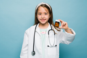 Cheerful kid aspiring doctor showing vitamins pills