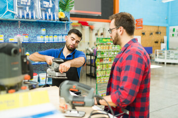 Smart hardware store worker helping a customer to buy power tools