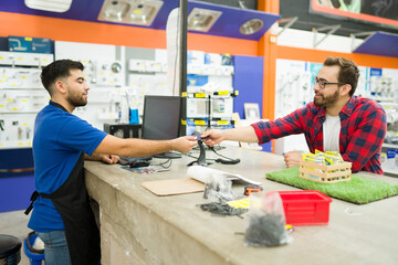 Happy customer buying at the hardware store with a credit card - obrazy, fototapety, plakaty