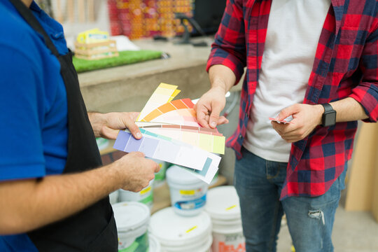 Male Employee With An Apron Advicing A Client Buying Paint At The Hardware Store