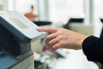 a woman uses a printer in the office. close-up of a woman's hand using buttons on a scanner printer