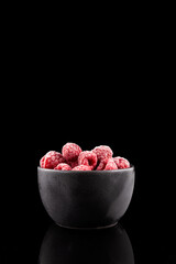 Frozen raspberries in dark bowl on black background. Frozen fruits - Clever Storage food. Selective focus, copy space. Vertical orientation