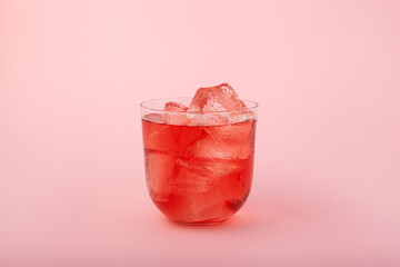 Glass of fruit ice tea. Red iced drink with fruit flavor on pink background. Refreshing lemonade...