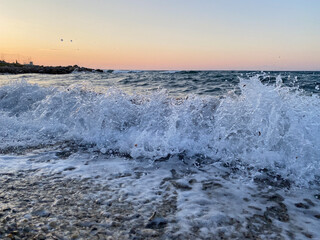Sea wave at sunset close-up with splashes, sea background