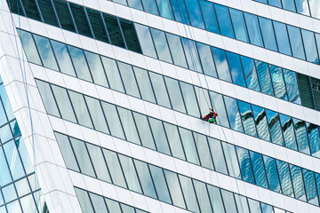 Industrial climber cleaning windows on the facade of an office building.