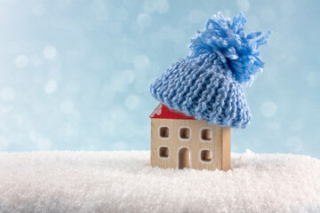 Figure of house and warm clothes on the snow against blurred lights. Concept of heating season....