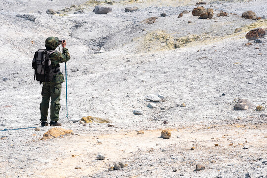 tourist taking pictures of the solfatara field on the slope of Mendeleev volcano, Kunashir island