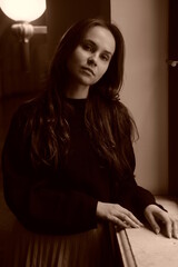 Retro sepia portrait. Girl stay near the old window