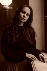 Retro sepia portrait. Girl stay near the old window