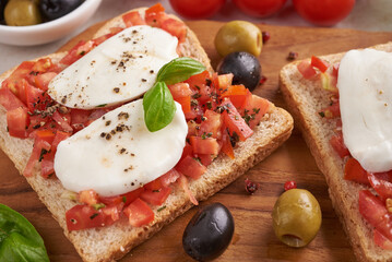 Bruschetta with tomatoes, mozzarella cheese and basil on a cutting board. Traditional italian appetizer or snack, antipasto. Caprese salad bruschetta. Top view with copy space. Flat lay.
