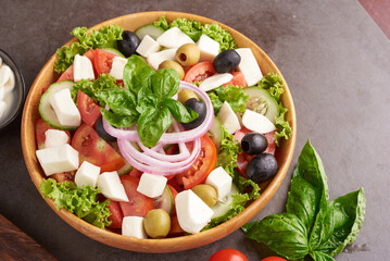 Classic greek salad of fresh vegetables, cucumber, tomato, sweet pepper, lettuce, red onion, feta cheese and olives with olive oil. Healthy food, top view