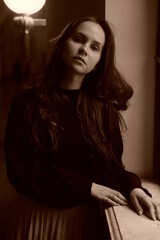 Retro sepia portrait. Girl stay near the old window