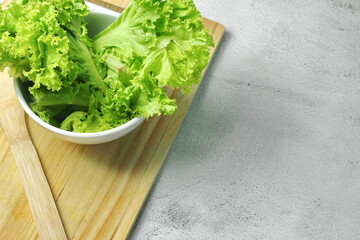 Lettuce placed in a white bowl and a cutting board on a white table. Vegetable salad. Vegetarian food. Clean food. Green vegetables.