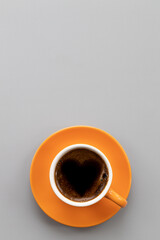 Orange cup of coffee with heart foam,isolated.Top view.Place for text.Vertical format.