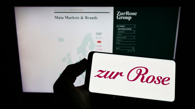 Stuttgart, Germany - 08-28-2022: Person holding smartphone with logo of Swiss pharmacy company Zur Rose Group AG on screen in front of website. Focus on phone display.