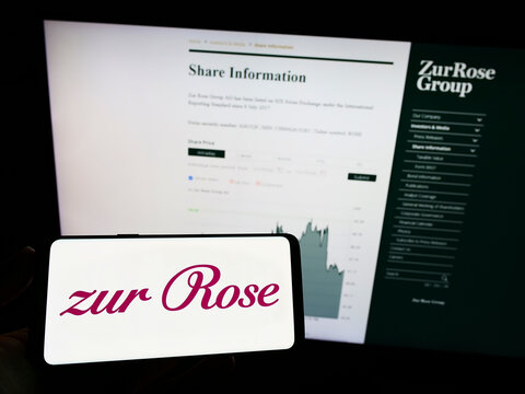 Stuttgart, Germany - 08-28-2022: Person holding mobile phone with logo of Swiss pharmacy company Zur Rose Group AG on screen in front of business web page. Focus on phone display.