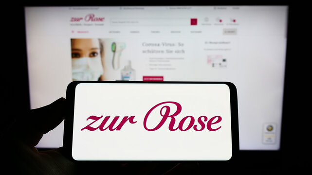 Stuttgart, Germany - 08-28-2022: Person holding cellphone with logo of Swiss pharmacy company Zur Rose Group AG on screen in front of business webpage. Focus on phone display.