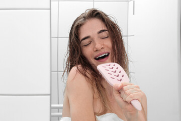 young beautiful girl in the bathroom with wet hair with a comb. in a white bath. hair care and health