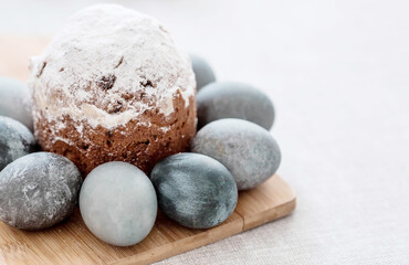 Fototapeta na wymiar Stylish grey Easter eggs in marble and concrete and a cake on a wooden stand. Coloring eggs with natural dye karkade tea. Environmental friendliness. Naturalness. The concept of happy Easter 2023.