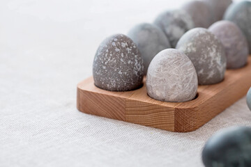 Stylish grey Easter eggs in marble and concrete on a wooden stand. Coloring eggs with natural dye karkade tea. Environmental friendliness. Naturalness. The concept of happy Easter 2023.