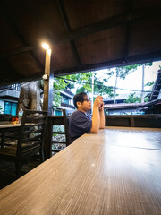 Young boy sitting at the table and using mobile phone. Looking serious.