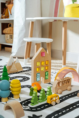 A toy town built in a children's room. Road, cars, trees and wooden blocks for children's  games in playroom. Educational game for baby and toddler in modern nursery.