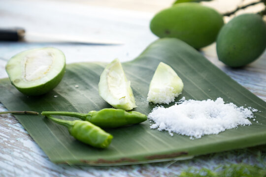 Some raw mango or kaccha aam with some ingrediants like chilli, salt, pudina and garden presly