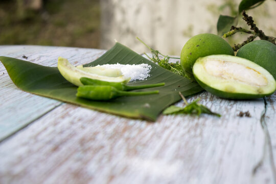 Some raw mango or kaccha aam with some ingrediants like chilli, salt, pudina and garden presly