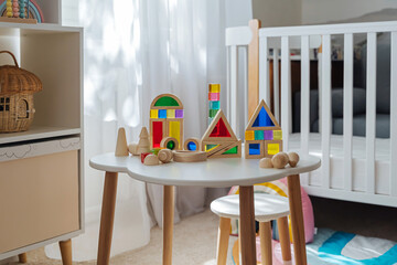 Playroom with toys. Wooden rainbow stacking blocks on the table in the kids room. Educational game for baby and toddler in modern nursery. Early development.