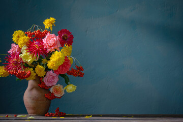 red and yellow flowers on jug in sunlight on background dark wall