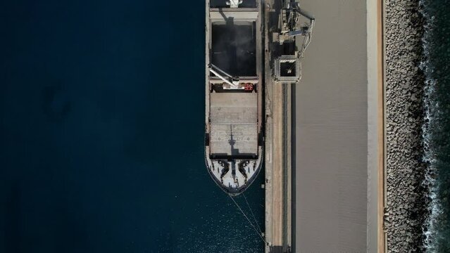 aerial shot over one of the ships that transport the merchandise and the cranes that load the cement. Factory located in Arguineguin on the island of Gran Canaria.