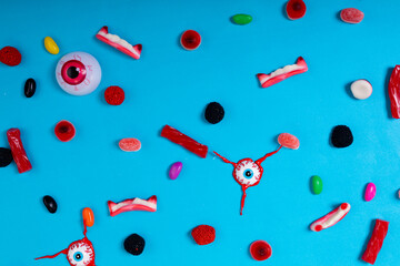 Multiple scary eyes toys and halloween candies on blue surface - Powered by Adobe