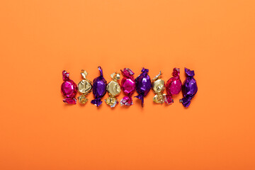 Close up of multiple halloween candies with copy space against orange background - Powered by Adobe