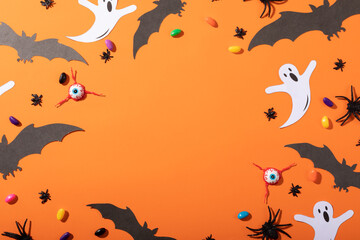 Obraz na płótnie Canvas Multiple halloween toys and candies with copy space on orange background
