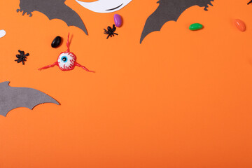 Multiple halloween toys and candies with copy space on orange background