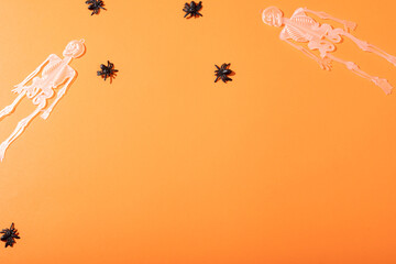 Multiple skeleton and spider toys with copy space against orange background - Powered by Adobe
